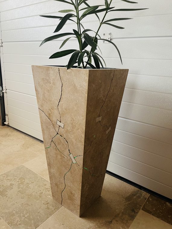 Totem Ligne de Vie, jardinière en travertin traversée par une fracture agrafée — photo d'atelier