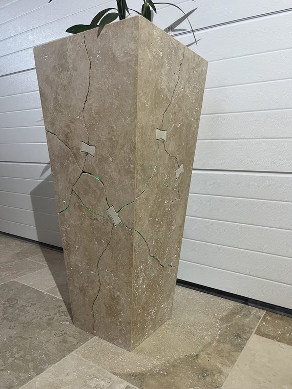 Totem Ligne de Vie, jardinière en travertin traversée par une fracture agrafée — photo d'atelier